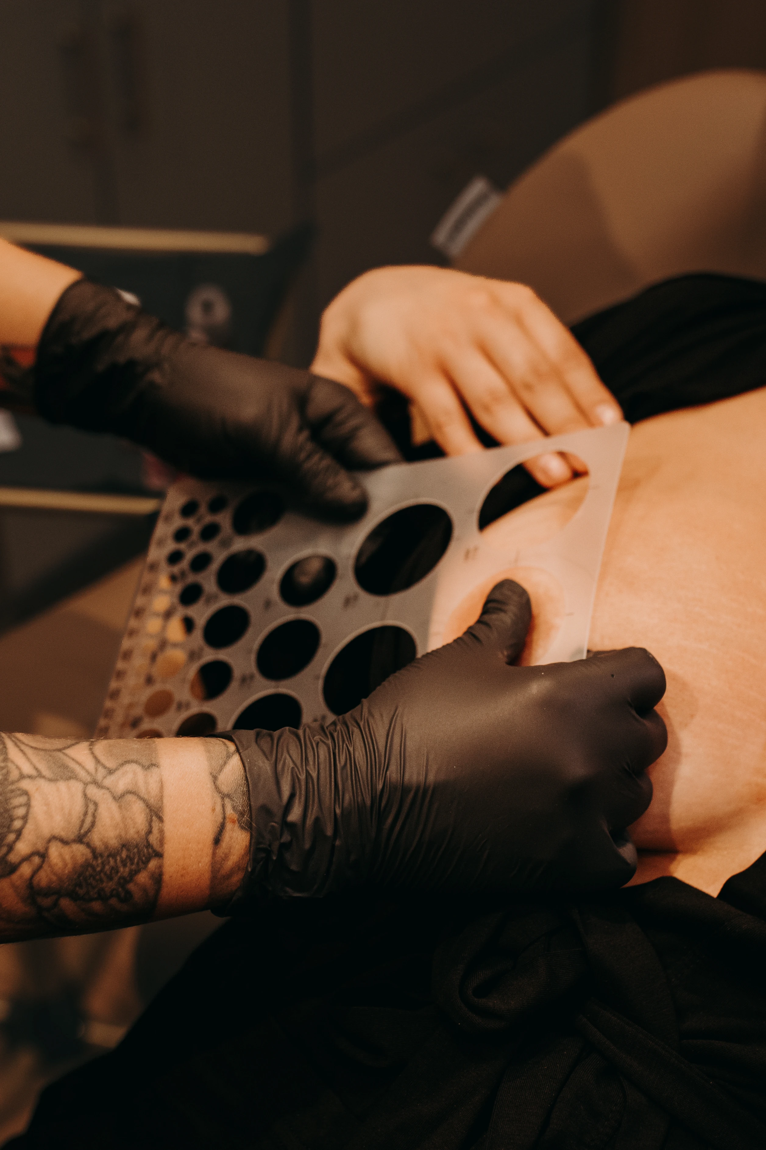 Danielle Payne checking areola sizing with a stencil before tattooing